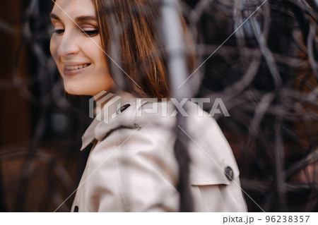 A happy stylish girl In a gray coat is sitting outside in an armchair 96238357