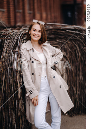 A happy stylish girl in a gray coat walks around the city A happy stylish girl in a gray coat walks around the city 96238419