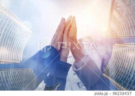 Three business people hit high five outside the office. Double exposure with light effect 96238437