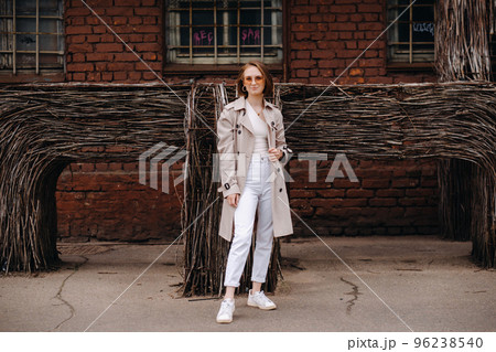 A happy stylish girl in a gray coat walks around the city 96238540