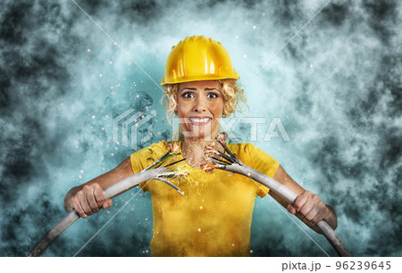 Worker girl with hat breaks an electric cable. Cyan background 96239645