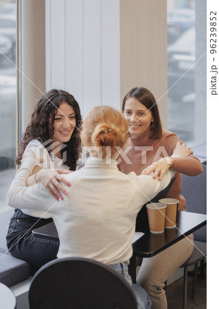 three female friends are talking in a coffee shop and drinking tea, moral support and caring friendship. mental health three female friends are talking in a coffee shop and drinking tea, moral support and caring friendship. mental health 96239852