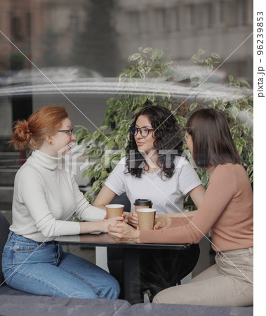 three female friends are talking in a coffee shop and drinking tea, moral support and caring friendship. mental health 96239853