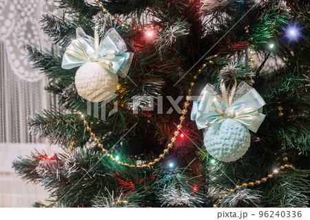 Cream and blue colored decorative Christmas balls on Christmas Tree among the garlands and fireflies at home, selective focus. Cream and blue colored decorative Christmas balls on Christmas Tree among the garlands and fireflies at home, selective focus. 96240336