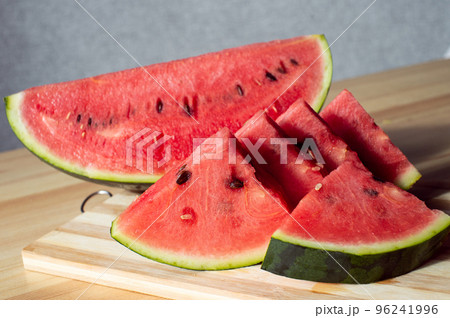 A sliced ripe watermelon is lying on a wooden table A sliced ripe watermelon is lying on a wooden table 96241996