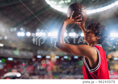 Basketball player throws the ball in the basket in the stadium full of spectators. 96243078