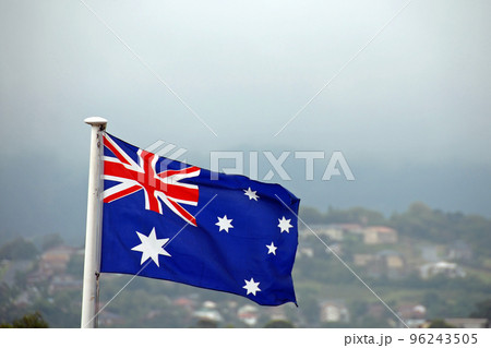 Australian flag set against a background of houses on a hill and sky. The Australian flag features six stars and the British union jack. Australian flag set against a background of houses on a hill and sky. The Australian flag features six stars and the British union jack. 96243505