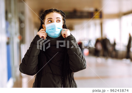 Girl in protective sterile medical mask on her face in quarantine city. Woman, wear face mask Girl in protective sterile medical mask on her face in quarantine city. Woman, wear face mask 96243874