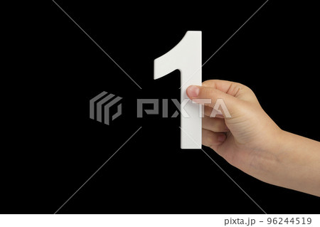 Number one in a hand isolated on a black background. Number one white in a child's hand on a black background. 96244519