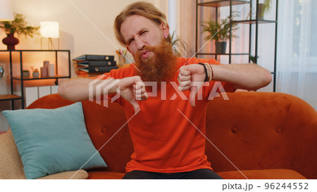 Upset young man showing thumbs down, dislike bad work, disapproval, dissatisfied feedback at home 96244552