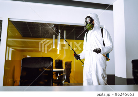 Disinfecting of office to prevent COVID-19, Man in protective hazmat suit with spray chemicals. Disinfecting of office to prevent COVID-19, Man in protective hazmat suit with spray chemicals. 96245653