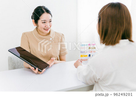 ネイルサロンでタブレットを使ってネイリストにカウンセリングを受ける女性 ネイルサロンでタブレットを使ってネイリストにカウンセリングを受ける女性 96249201