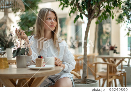 Attractive girl drinking tea with cake in cafe 96249390