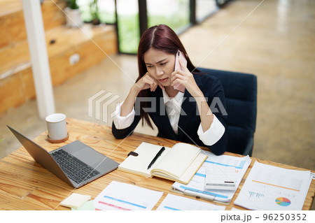 businesswoman showing a serious expression while talking on the phone. 96250352