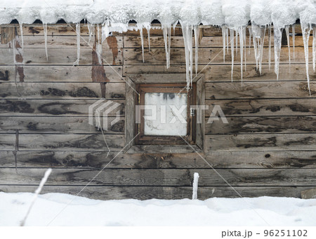 A small window and icicles on the roof an old wooden stable in winter A small window and icicles on the roof an old wooden stable in winter 96251102