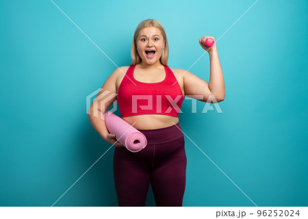 Fat girl does gym at home. satisfied expression. Cyan background