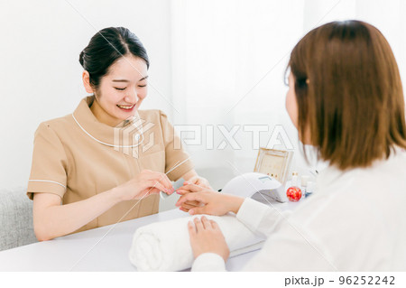 ネイルサロンでサンディングするネイリストと施術を受ける日本人女性 96252242