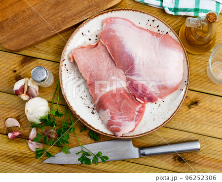 Raw pork fillet on plate with herbs, peppers and knife Raw pork fillet on plate with herbs, peppers and knife 96252306