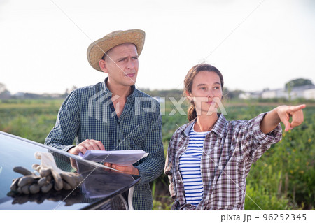 Farmers discussing documents near car on farm 96252345