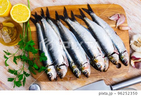 Raw sardines on wooden cutting board 96252350
