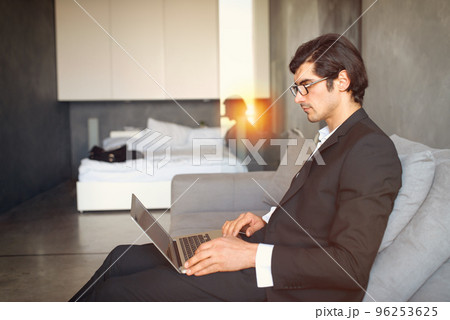 Young businessman sitting on the floor while working from home with a laptop 96253625