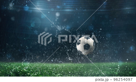 Close up of a soccer ball rolling on the playing field on a rainy night Close up of a soccer ball rolling on the playing field on a rainy night 96254097