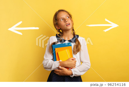 Young student is confused about the right arrow to select. Yellow background 96254116