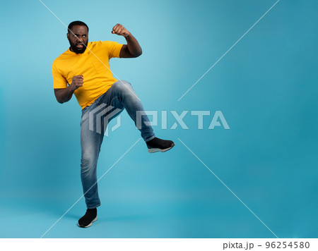 Man is angry and fights with kicks. Blue background Man is angry and fights with kicks. Blue background 96254580