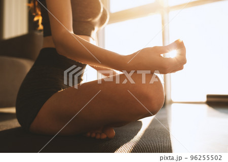 Young girl relaxing in yoga position in front of a bright window Young girl relaxing in yoga position in front of a bright window 96255502