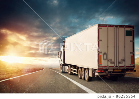 White truck moving on the road in a natural landscape at sunset. 96255554