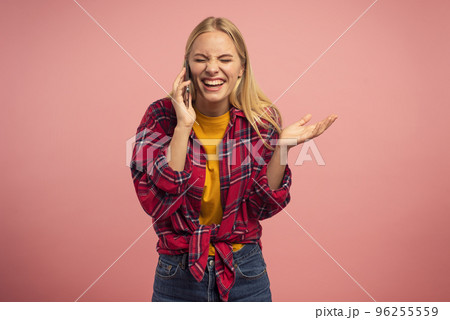 Very happy girl talk with a friend on the mobile phone. Pink studio background. Concept of joyful 96255559