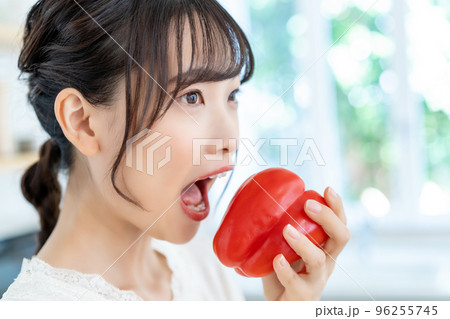 キッチンでパプリカをかじる若い女性 キッチンでパプリカをかじる若い女性 96255745