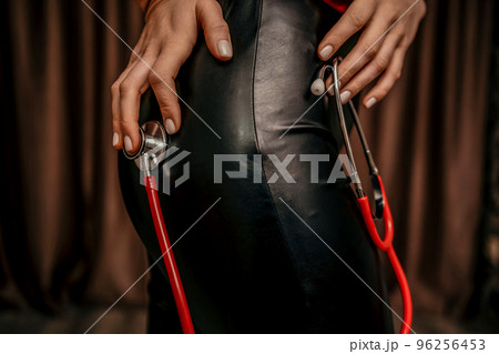 Young woman in red corset and black leather pants with a phonend 96256453