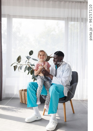 an African-American doctor examines a child with a stethoscope. 96257110