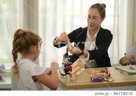 Friendly teachers help elementary school students in class. Friendly teachers help elementary school students in class. 96258016