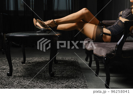 Woman in stockings is sitting on the sofa with her feet on the coffee table 96258041