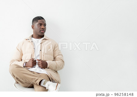 Model photoshoot. Confident man portrait. Trendy guy in beige outfit sitting in studio 96258148