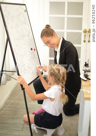 A  teacher teaches her young daughter to paint with colorful pens in the school classroom. concept of child rearing education By being a creative and artistic child. 96258240