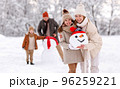 Cheerful family parents with kids in snowy winter park have fun and actively relax outdoors 96259221