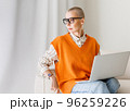 Beautiful woman freelancer in glasses with very short hair working at laptop at home 96259226