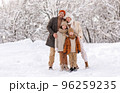 Happy family in warm clothes smiling at camera while playing on fresh air in winter snowy forest 96259235