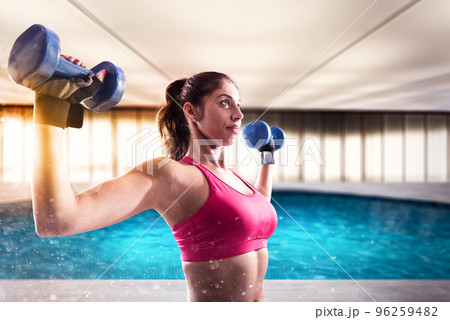 Muscular woman is training with weights dumbbells 96259482
