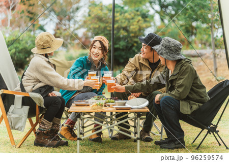 仲間と一緒にキャンプ場でビールで乾杯するアジア人の男女 96259574