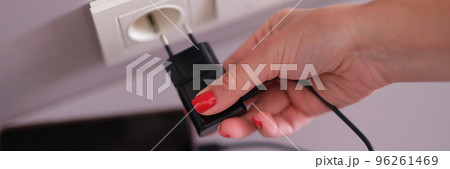 Woman hand plugging mobile phone charger into socket closeup Woman hand plugging mobile phone charger into socket closeup 96261469