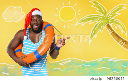 Black man in swimsuit ready to go in a sunny place for christmas. Yellow background 96266055