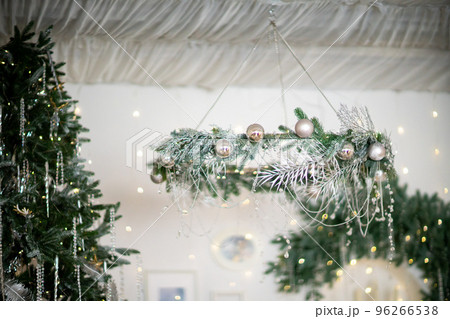 Close-up of a festively decorated outdoor Christmas tree with balls on a blurred sparkling fairy background. Defocused garland lights, bokeh effect. 96266538