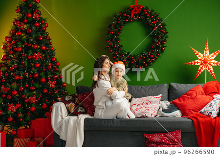 Mother sitting on a sofa with her son in living room decorated for Christmas Mother sitting on a sofa with her son in living room decorated for Christmas 96266590