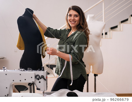 Seamstress works to new clothes commissioned by a client in a shop 96266679