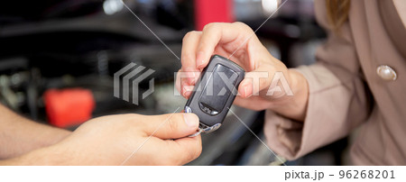 Closeup hands of mechanic giving key to customer after repair car at garage, auto service. Closeup hands of mechanic giving key to customer after repair car at garage, auto service. 96268201