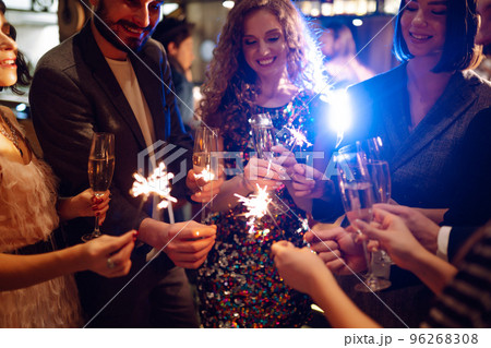 Glowing sparkles in hands. Group of happy people enjoying party with fireworks. Winter holiday. 96268308